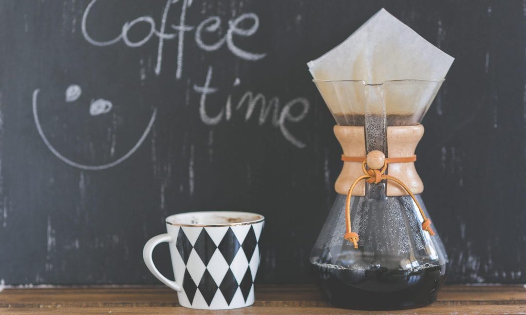 A Photo of a checkered coffee cup next to a big clear glass container